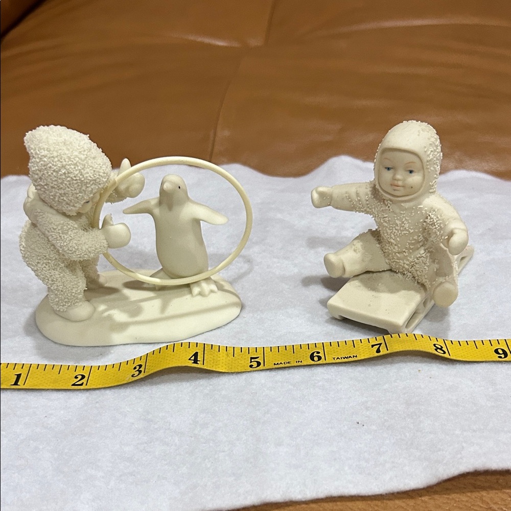 2 Snow babies: Penguin trainer, and baby on a sled.
